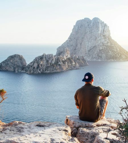 Rear View of Man Sitting on Rock by Sea